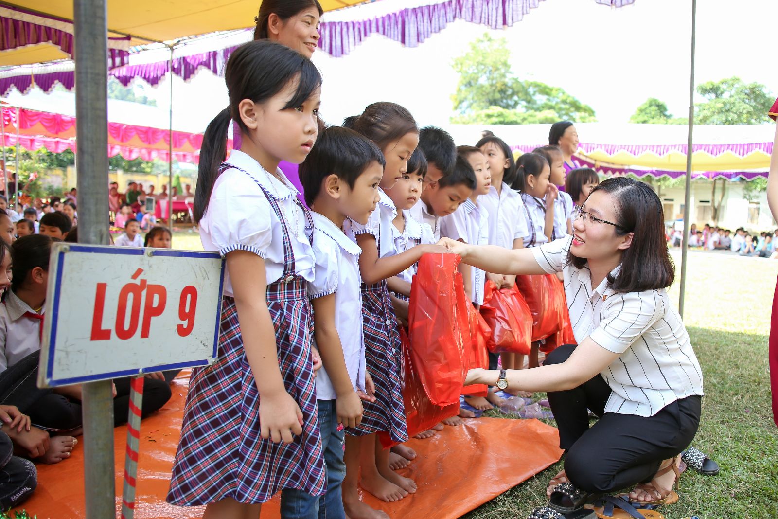 Bà Trần Cẩm Vân đại diện công ty Bảo Tín Minh Châu tặng quà cho các em học sinh xã Hùng Tiến